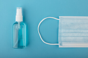 Medical mask and sanitizer on a blue background. Antiseptic and protective disposable mask on blue background. Hygiene concept. Prevent spread of germs and bacteria and avoid infections coronavirus.