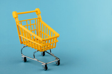 Empty yellow shopping basket on a blue background. Shopping and crisis concept