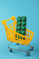 Shopping cart loaded with pills drugs or medicine on yellow background.antibiotics. Women's health, medicine and healthcare concept. Top view, copy space for text.