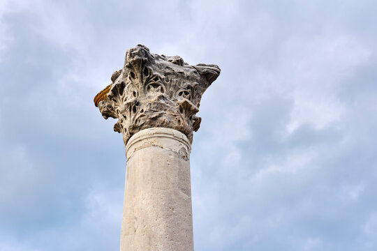 weathered capital of an antique column in the Corinthian order style against the sky