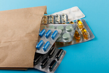 Heap of pills in blister packaging on blue desk. Concept of healthcare, drug addict or chemical weapon. Close-up. 