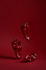 Three red peppers paprika on a red background. Vertical photo