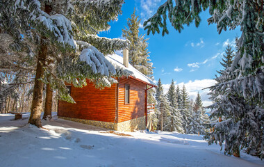 Fantastic winter landscape with wooden house in snowy mountains. Christmas and winter vacations...