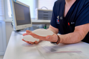 doctor holds the breast implants in his hands