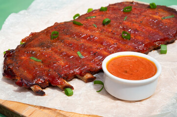 Close up board with pork ribs grilled with BBQ sauce, peanuts and jalapeno
