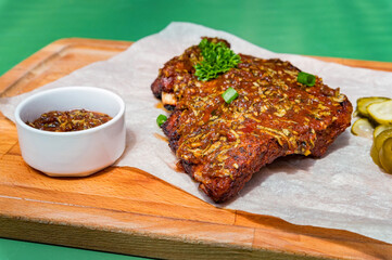 Close up board with pork ribs grilled with BBQ sauce, peanuts and jalapeno