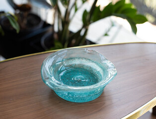 Turquoise  blue crystal glass bowl ashtray on a wooden table