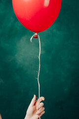 red balloon in hand on a green background flies up close-up
