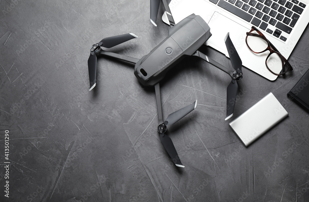 Wall mural modern drone with video camera and laptop on grey stone table, flat lay. space for text