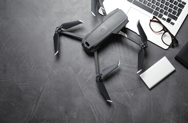 Modern drone with video camera and laptop on grey stone table, flat lay. Space for text