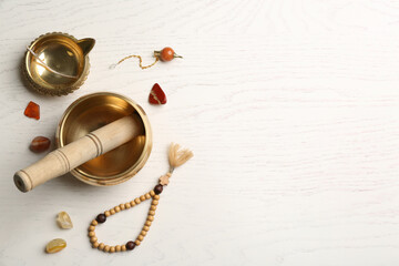 Flat lay composition with golden singing bowl on white wooden table, space for text. Sound healing