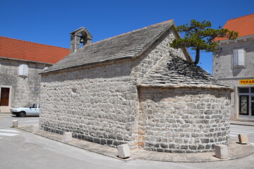 Fototapeta na wymiar A church with a tree growing from roof on the island of Brac, Croatia 