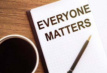 EVERYONE MATTERS. Text on notepad on wooden desk.