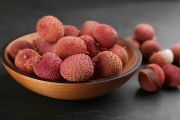 Fresh ripe lychee fruits in wooden bowl on black table