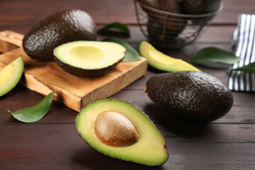 Fresh whole and cut avocados on wooden table