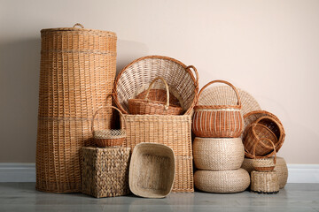 Many different wicker baskets made of natural material on floor near light wall