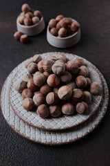 Hazelnuts in a ceramic plate . Lots of nuts on a dark background. Vertical photo. Food with a high protein concentrate. Natural protein food.