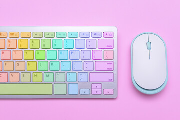 Colorful computer keyboard and mouse on pink background