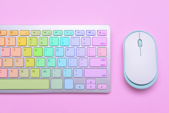 Colorful computer keyboard and mouse on pink background