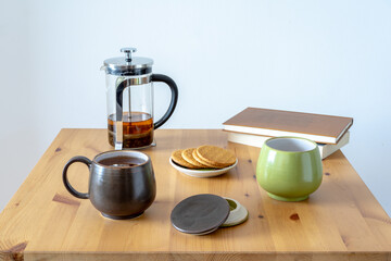 Tea time: Tea table with two teacups, biscuits, books and a teapot