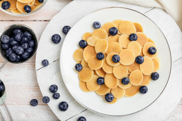 Plate of tasty pancakes with fresh blueberry on light wooden background, closeup