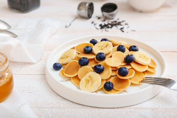 Plate of tasty pancakes with fresh blueberry and banana on light wooden background, closeup