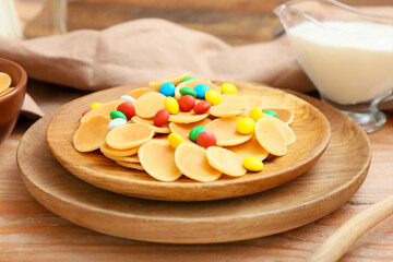 Plate of tasty pancakes with colorful candies on wooden background, closeup