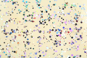 Shiny glitter on beige background, top view