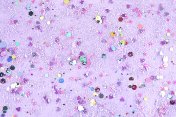 Shiny glitter on lilac background, top view