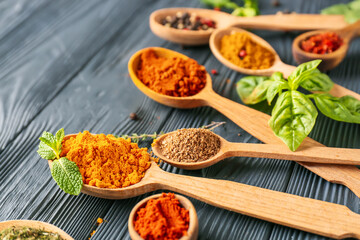 Spoons with different spices on dark wooden background