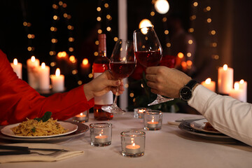Couple clinking glasses of wine in restaurant, closeup. Romantic dinner