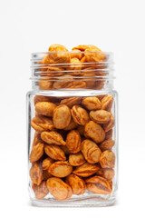 Roasted Crunchy Peanuts in a glass jar, made with peanuts. Pile of Indian spicy snacks (Namkeen), under backlight, front view, against the white background.