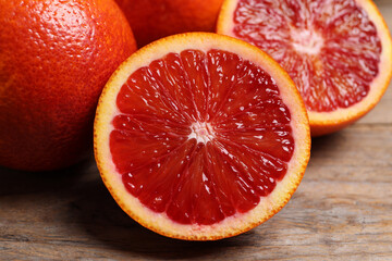 Whole and cut red oranges on wooden table, closeup