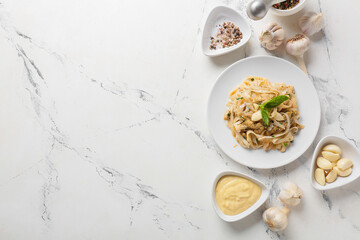 Plate with tasty noodles, chicken and garlic sauce on light background
