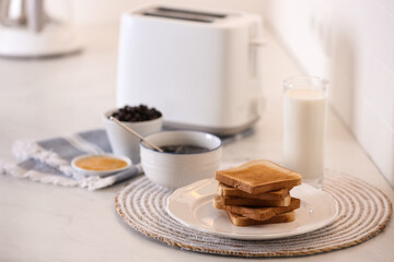 Modern toaster and delicious breakfast on table in kitchen