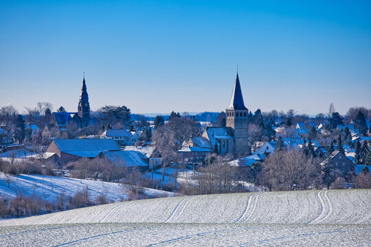 the catholic and protestant church of homberg in winter with snow and blue sky and sun	