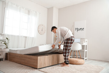 Man putting soft orthopedic mattress on bed