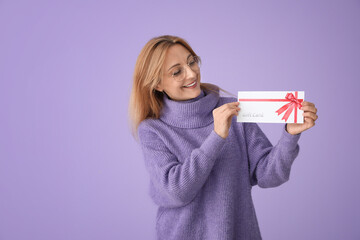 Mature woman with gift card on color background