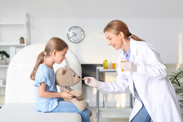 Pediatrician giving medicine to little girl in clinic