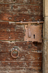 Primo piano di un’antica serratura a chiave, chiavistello e battente arrugginiti su un antico portone di un castello