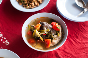Top view of Thai style Hot and sour Tilapia fish soup (Clear soup )with red background