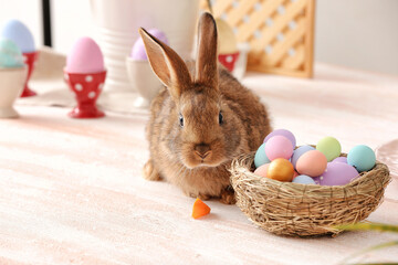 Cute rabbit and nest with Easter eggs on table