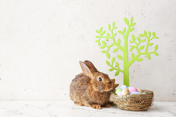 Cute rabbit, decor and Easter eggs on light background