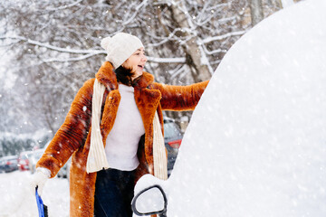 Bad weather conditions in winter. Mature woman in brown red artificial fur coat and white knitted...