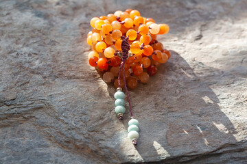 Orange stone beads mala necklace on grey rocky background