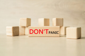 the word don't panic is written on a wooden cubes structure. Cube on a bright background. Can be used for business, MEDICINE, financial concept. Selective focus.