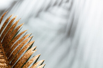 Gold palm leaves and shadows on a blue wall background.