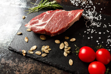 raw pork with spices for cooking on a fire or oven on a dark stone background