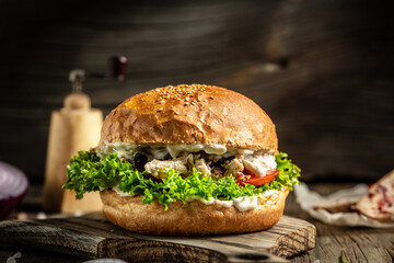 Chicken burgers with mustard, olives and cream sauce served on paper on a wooden board. American food concept. fast food meal. banner, menu, recipe, place for text