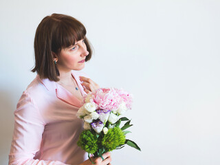 Young woman holding beautiful pastel peony bouquet on light gray background